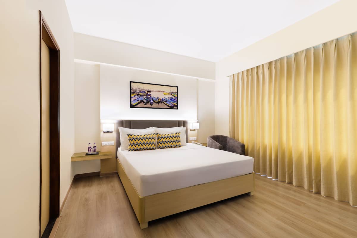 A hotel room with a bed, bedside tables, a painting, and a curtain.