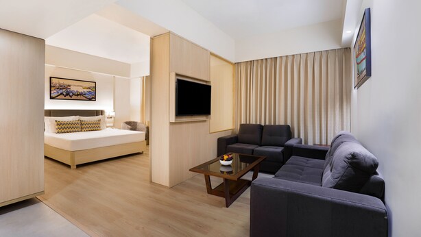 A modern hotel room with a bed, a sofa, a TV, and a painting on the wall. - Keys Lite Sreekanya Visakhapatnam (Visakhapatnam)