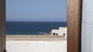 A view of the sea from a balcony with a building in the foreground. - Cycladic sea view house (Naxos)