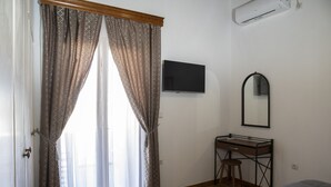 A bedroom with a bed, a desk with a chair, a television, and a mirror. - Cycladic sea view house (Naxos)
