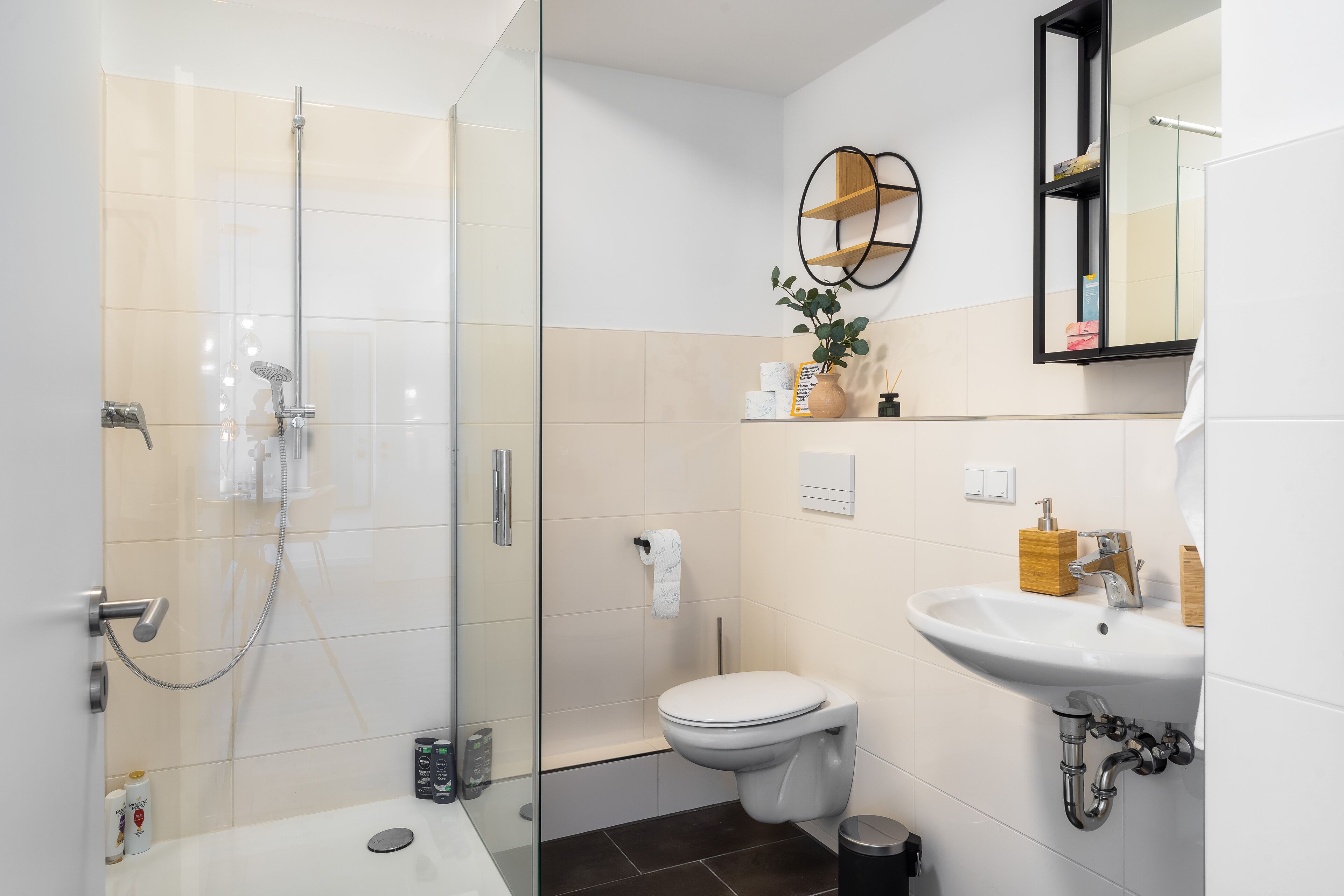 A modern bathroom with a glass-enclosed shower, a toilet, and a sink.