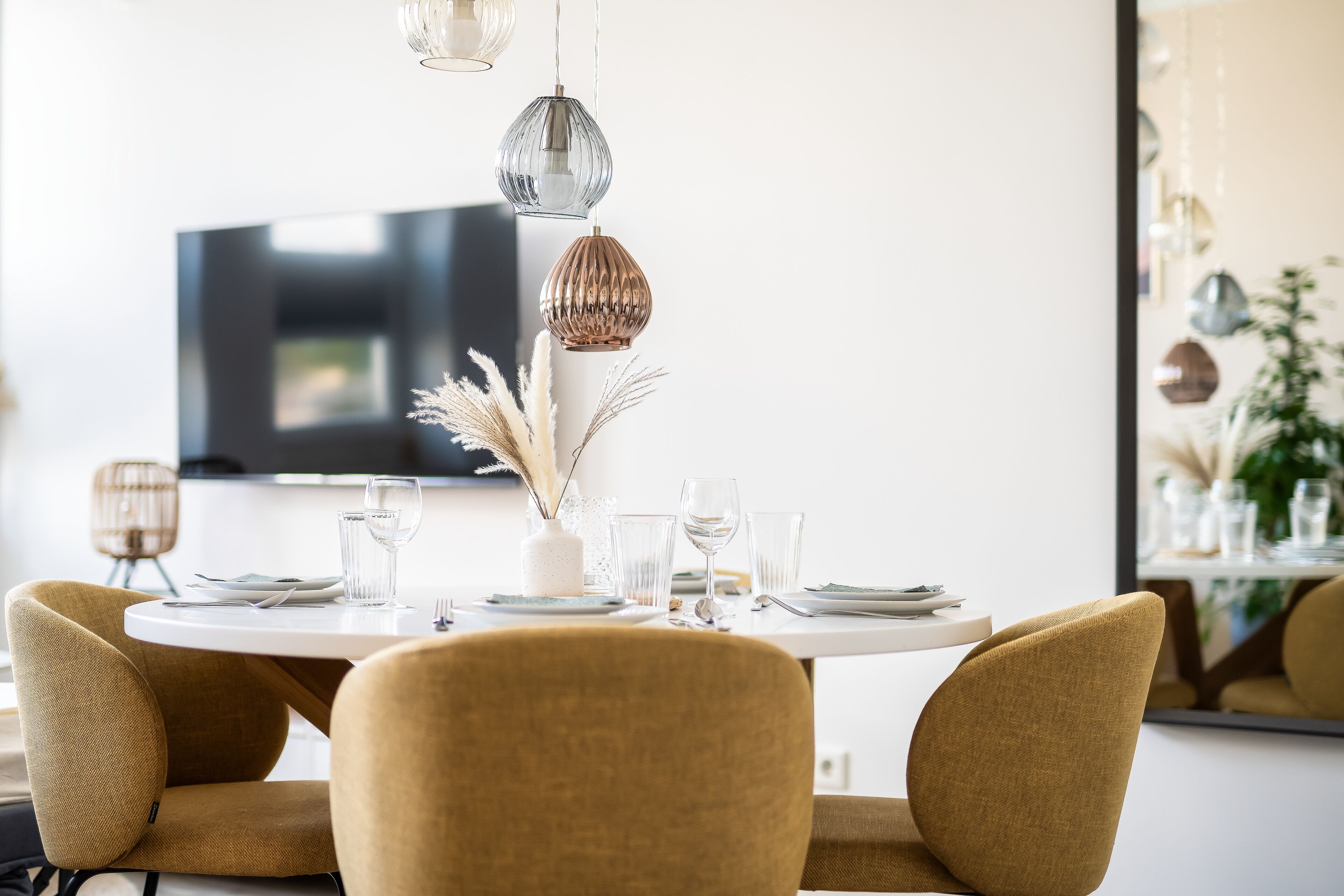 A dining area with a round table, four chairs, and hanging pendant lights.