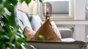 Ein Sofa mit einem gemusterten Kissen, einer Lampe und einem Fenster im Hintergrund.