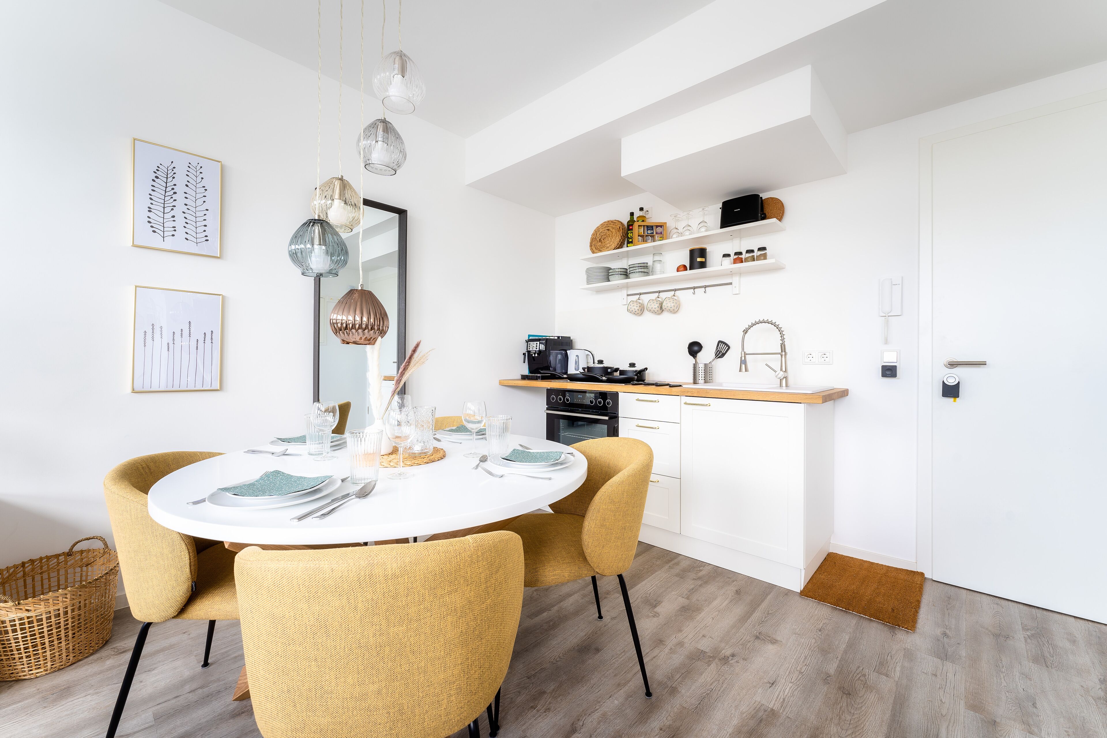 A modern kitchen with white cabinetry, a dining area with yellow chairs, and a white table set for four.