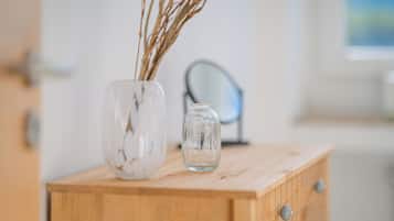 Un meuble en bois contenant deux vases en verre avec des plantes séchées.