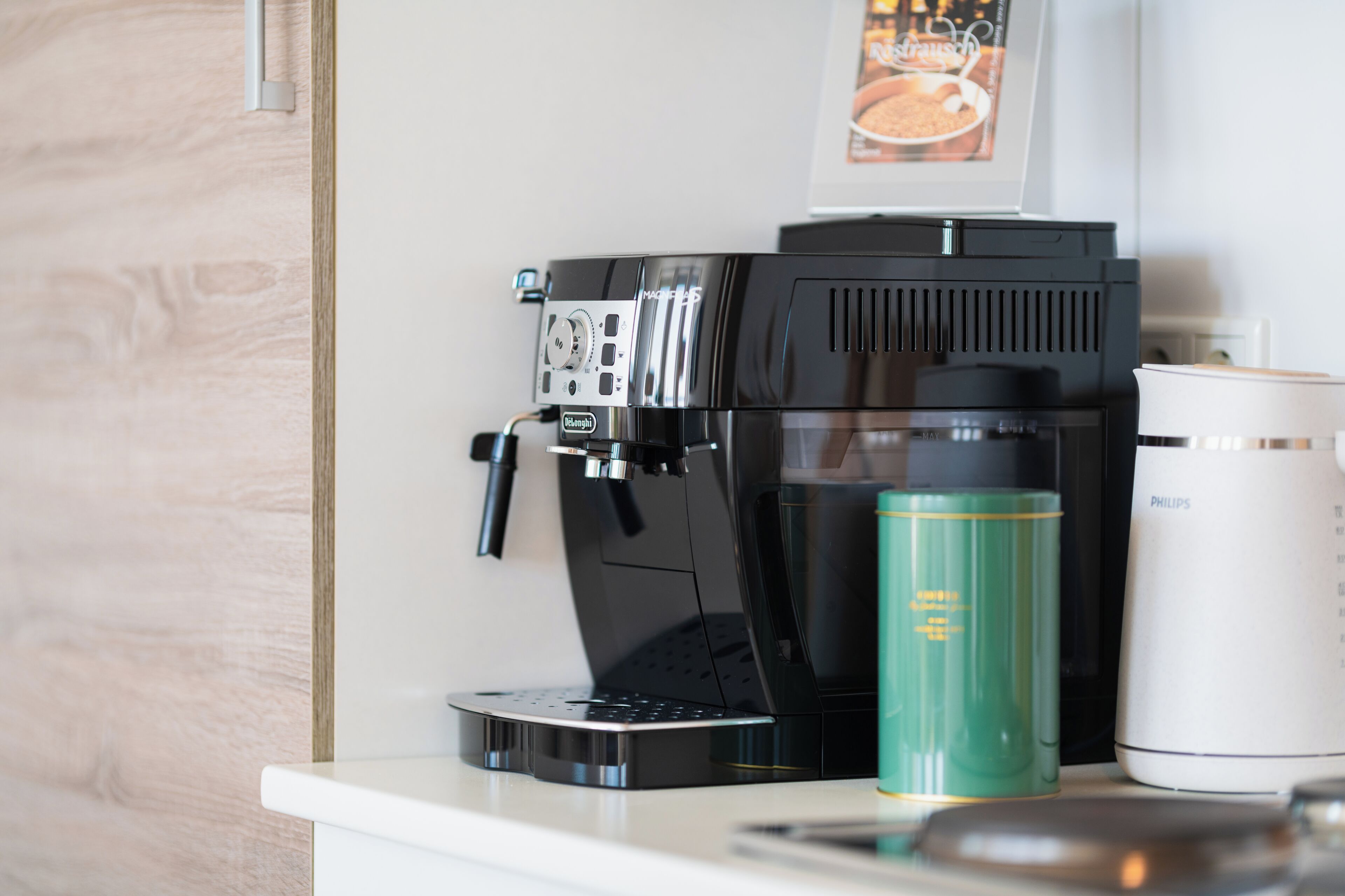 A coffee maker, a green water bottle, and a white thermos on a countertop.