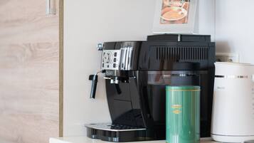 Una macchina per caffè, una borraccia verde e un thermos bianco su un piano di lavoro.