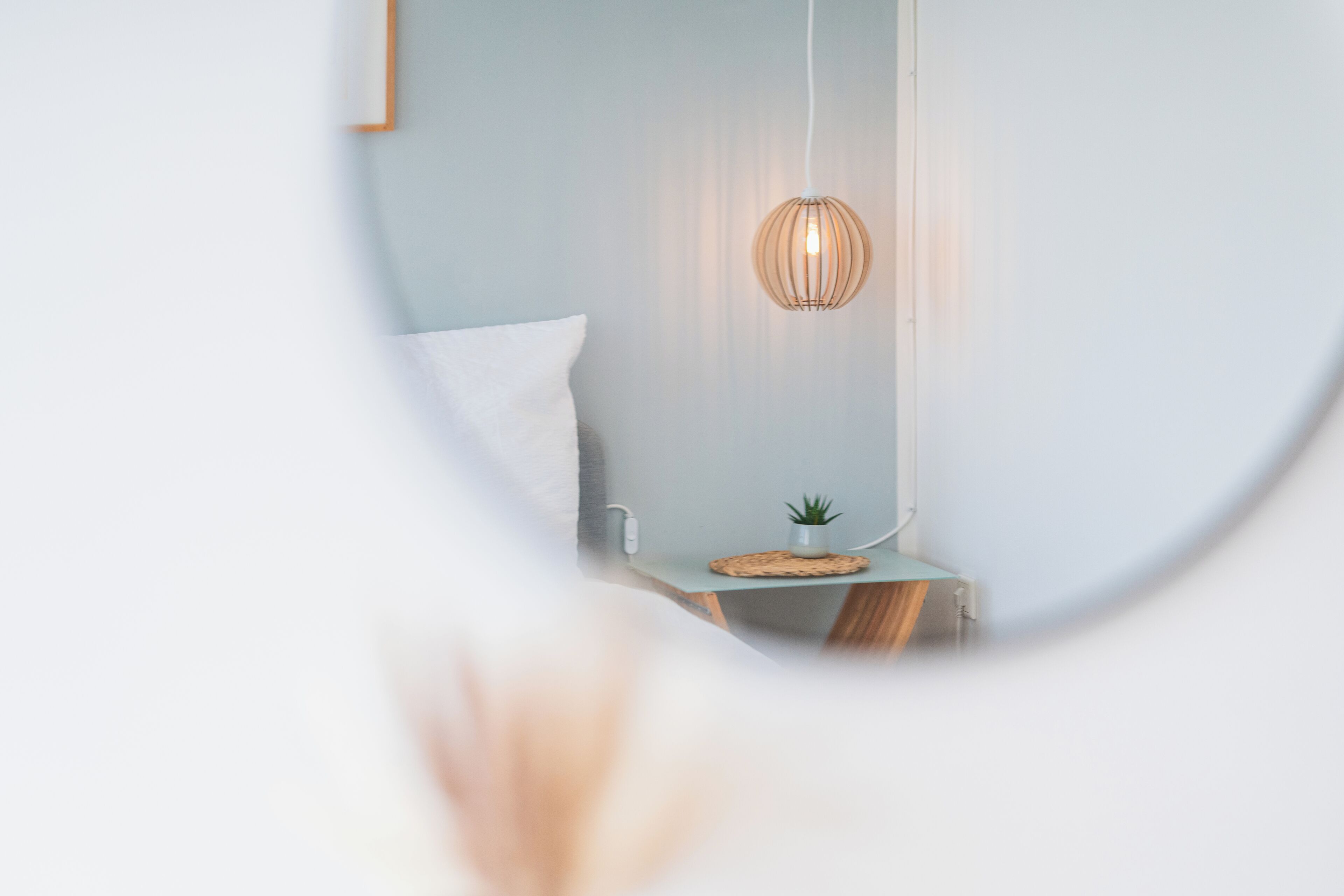 A bedroom with a bed, bedside table, lamp, and a small plant.