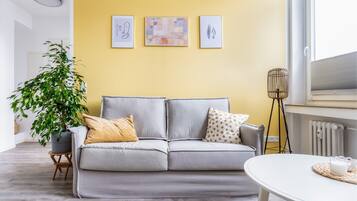 A living room with a grey sofa, a potted plant, and a table with a tray.