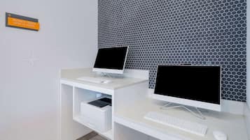 A business center with two desktop computers, a keyboard, and a mouse on a white desk.