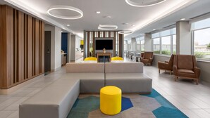 A modern lobby with a sectional sofa, a coffee table, and a flat-screen TV. - Microtel Inn & Suites By Wyndham Rehoboth Beach (Rehoboth Beach)