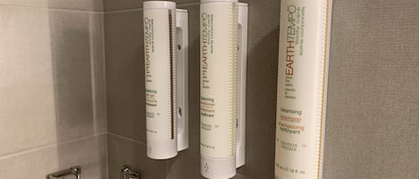 Three Earth7 body care products on a bathroom wall.