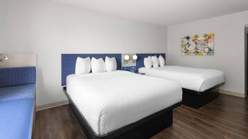 Een hotelkamer met twee bedden, een bureau, een stoel, een spiegel en een kunstwerk aan de muur.