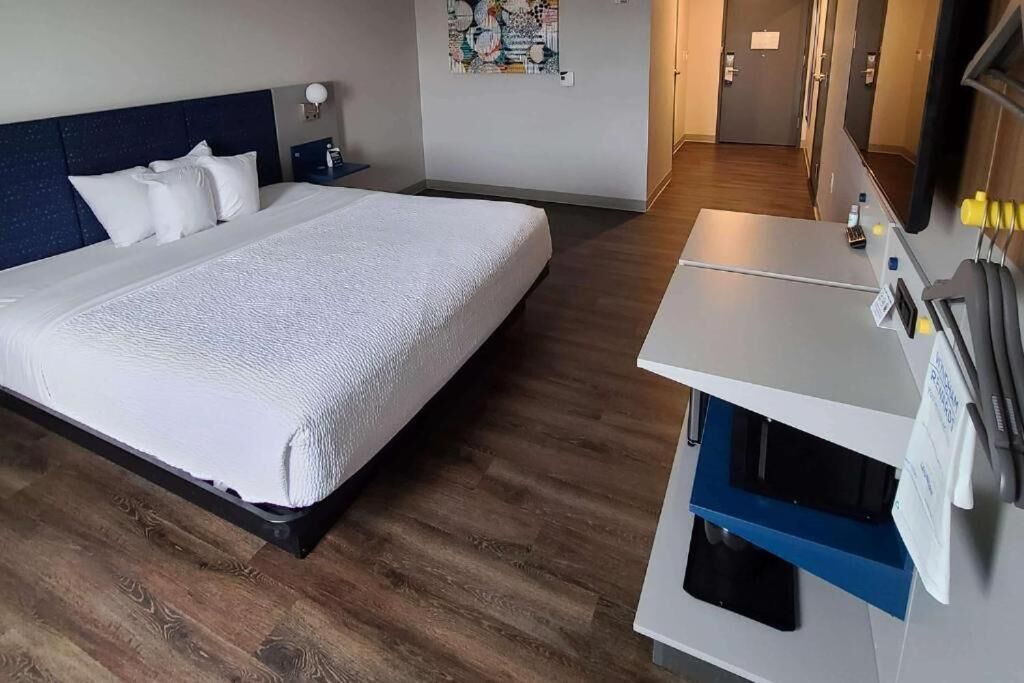 Une chambre d’hôtel avec un grand lit, un bureau avec un ordinateur et un miroir.