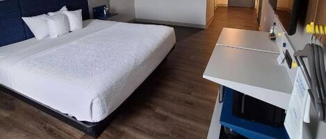 Une chambre d’hôtel avec un grand lit, un bureau avec un ordinateur et un miroir.
