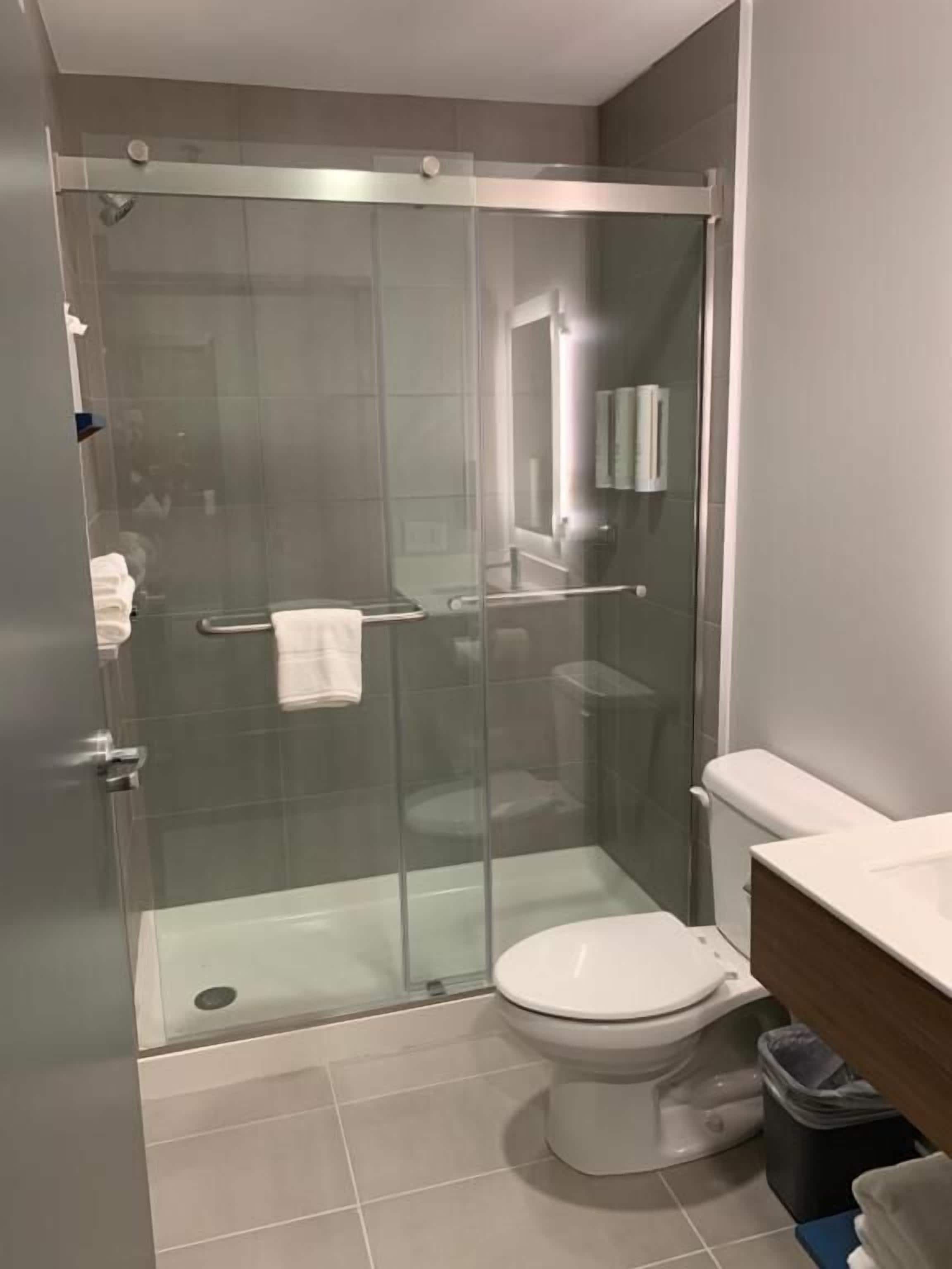 Ein modernes Badezimmer mit einer gläsernen Dusche, einer weißen Toilette und einem Holzbadezimmer-Möbel.