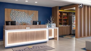 A reception desk with a digital screen, a map artwork, and a sign for 'MICROHOTEL BY WYNDHAM'. - Microtel Inn & Suites By Wyndham Rehoboth Beach (Rehoboth Beach)
