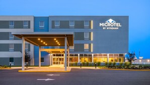 A modern microhotel with a covered entrance, multiple windows, and a sign indicating it's by Wyndham. - Microtel Inn & Suites By Wyndham Rehoboth Beach (Rehoboth Beach)