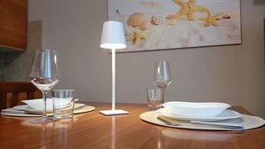 A dining table with a white table lamp, wine glasses, and plates set for a meal. - Studio apartment "Holiday Sea" with Terrace & A/C (Diano Marina)