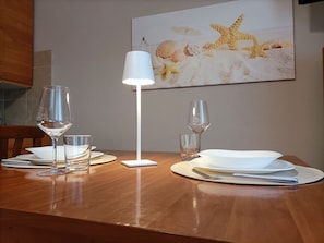 Una mesa de comedor con una lámpara blanca, copas de vino y platos dispuestos para una comida.