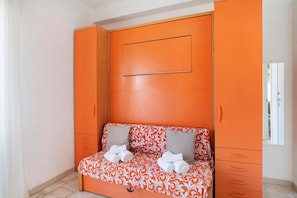 Una habitación con cama, armario y una mesita con toallas.
