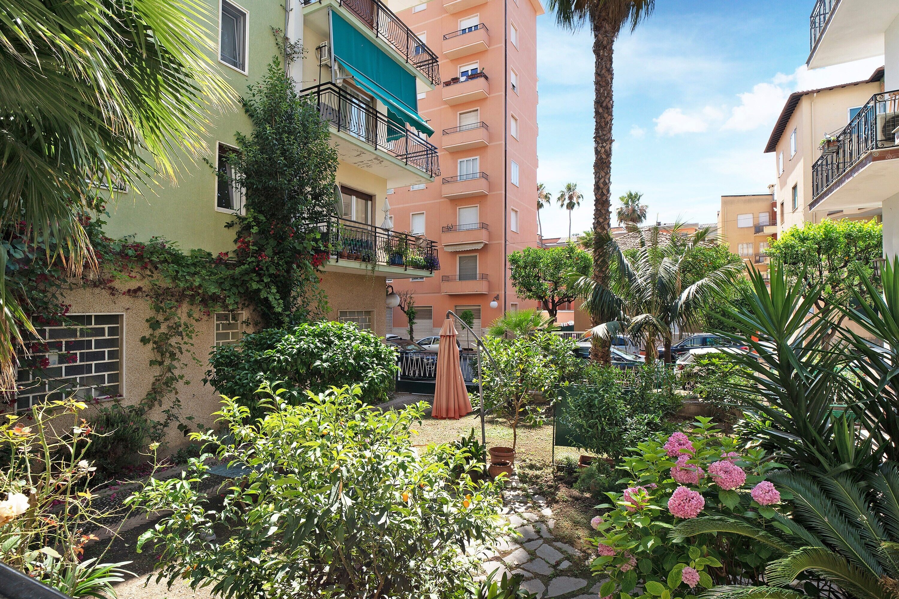 Une cour intérieure avec un palmier, un petit jardin et un bâtiment doté de balcons.