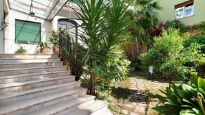 A set of stone steps leading to a building with a green shuttered door, a metal railing, and potted plants. - Studio apartment "Holiday Sea" with Terrace & A/C (Diano Marina)
