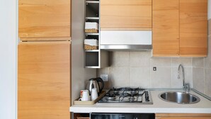 A kitchen with wooden cabinets, a stainless steel sink, a gas stove, and a built-in oven. - Studio apartment "Holiday Sea" with Terrace & A/C (Diano Marina)