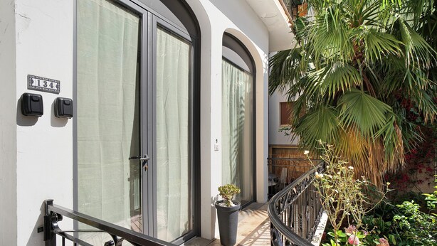 A hotel entrance with a number sign, a potted plant, and a staircase leading to a balcony with plants. - Studio apartment "Holiday Sea" with Terrace & A/C (Diano Marina)