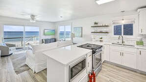 A modern kitchen with a large island, white cabinetry, and a view of the ocean. - Beach Front with Balcony and Grill (Panama City Beach)
