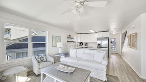 A spacious living area with a white sofa, a coffee table, and a view of the outside. - Beach Front with Balcony and Grill (Panama City Beach)