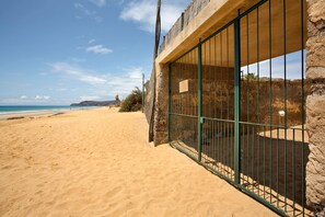 A beachside property with a stone wall, a metal gate, and a view of the ocean.