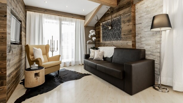 Una sala de estar moderna con techo de madera, un sofá, un sillón, una lámpara de pie y un tapete negro.