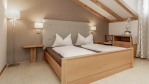 Un dormitorio con cama de madera, lámparas de noche, mesita de noche, una silla y un pequeño armario de madera.