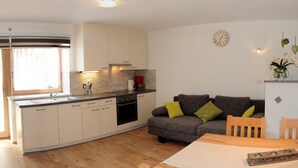 Eine moderne Küche mit Einbauofen, ein Essbereich mit Tisch und Stühlen sowie ein Wohnzimmer mit Sofa.