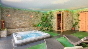 Wellnessbereich mit Whirlpool, Korbsesseln, Steinwänden und Topfpflanzen.