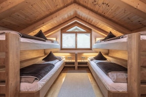 Une chambre mansardée chaleureuse avec des lits superposés en bois, un puits de lumière et un plancher recouvert de moquette.
