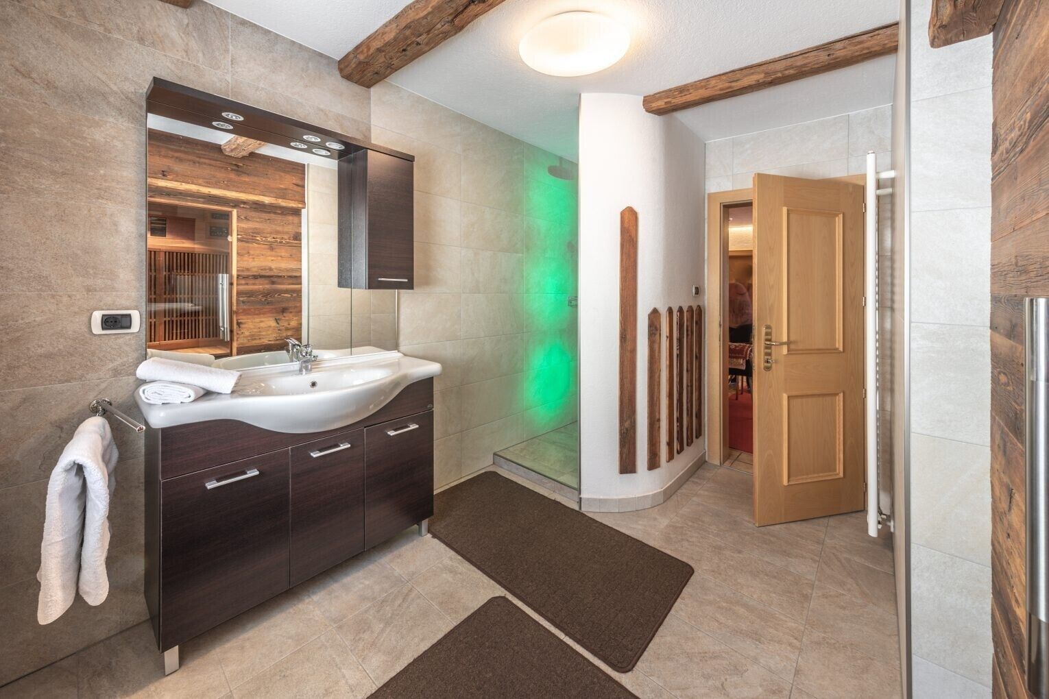 Un baño moderno con lavamanos integrado, detalles de madera y zona de ducha a la vista.
