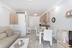 Eine moderne Wohnung mit Wohnbereich, Essplatz, Küchenzeile und Fernseher.