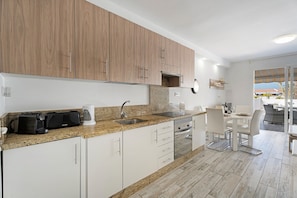A modern kitchen with granite countertops, white cabinetry, and a dining area with a table and chairs.