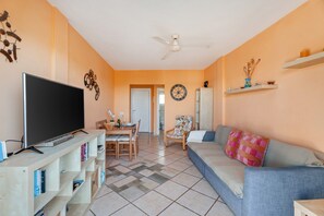 A living room with a television, sofa, and dining area.