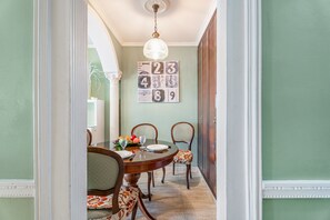A dining area with a round table, chairs, a chandelier, and a wall with numbered decorations.