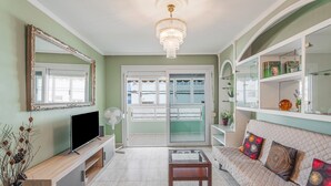A living room with a TV, a fan, a coffee table, a sofa with patterned cushions, and a chandelier. - Vacation Apartment 'Ceyla 214' with Sea View, Private Terrace and Wi-Fi (Arona)