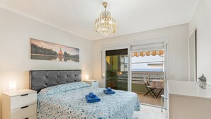 A bedroom with a bed, bedside tables, a chandelier, a painting, and a balcony with a view. - Vacation Apartment 'Ceyla 214' with Sea View, Private Terrace and Wi-Fi (Arona)
