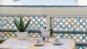 A balcony with a potted plant, a coffee maker, and two cups on a patterned tablecloth. - Vacation Apartment 'Ceyla 214' with Sea View, Private Terrace and Wi-Fi (Arona)