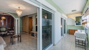 A spacious room with a large sliding glass door, a dining area with chairs and a table, and a small kitchenette. - Vacation Apartment 'Ceyla 214' with Sea View, Private Terrace and Wi-Fi (Arona)