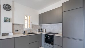Eine moderne Küche mit grauen Schränken, einem eingebauten Backofen und einem Fenster.