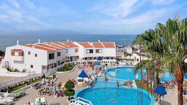 A resort with a swimming pool, lounge chairs, and a view of the sea. - Vacation Home "Club Atlantis 223" with Sea View, Shared Pool & Wi-Fi (Adeje)