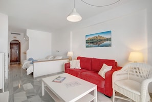 Un salon moderne avec un canapé rouge, un fauteuil blanc et une table basse blanche.