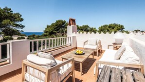 Una terraza con mobiliario exterior, una mesa con limones y vistas al mar.